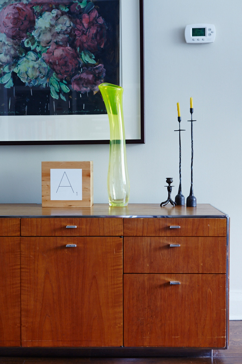 Neat arrangements of art and objets accentuate the home. A ’70s credenza is topped with a vase by Jeff Goodman and iron candlesticks from Hollace Cluny. Painting by Tony Sherman.