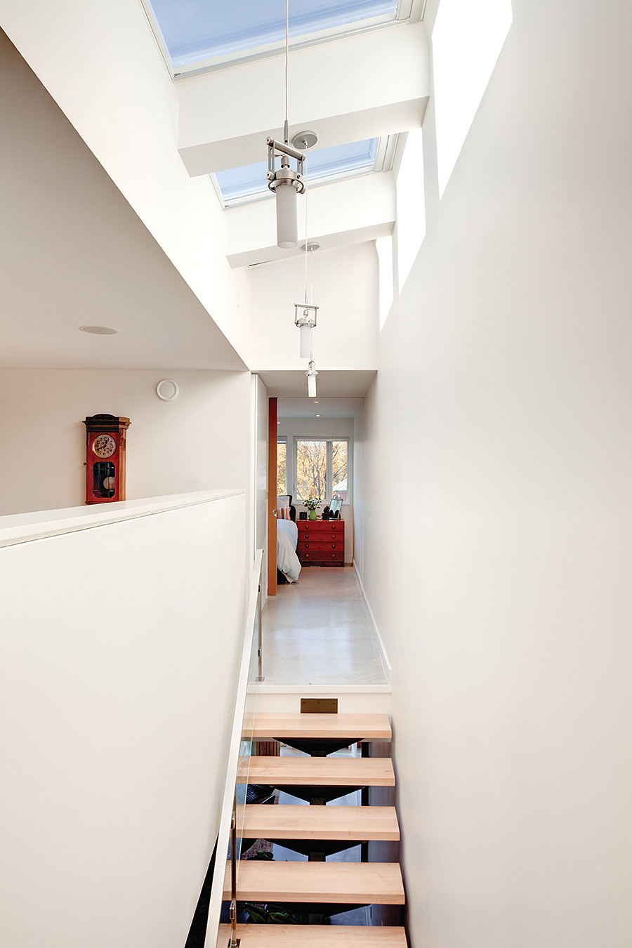 The stairwell is lit by three remote-controlled skylights by Inline Windows. Boomerang pendants from Sistemalux.