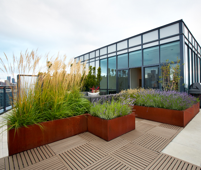 A wraparound rooftop patio in Corktown was divided into “rooms” using stone tile flooring and Corten steel planters filled with quivering feather grass.