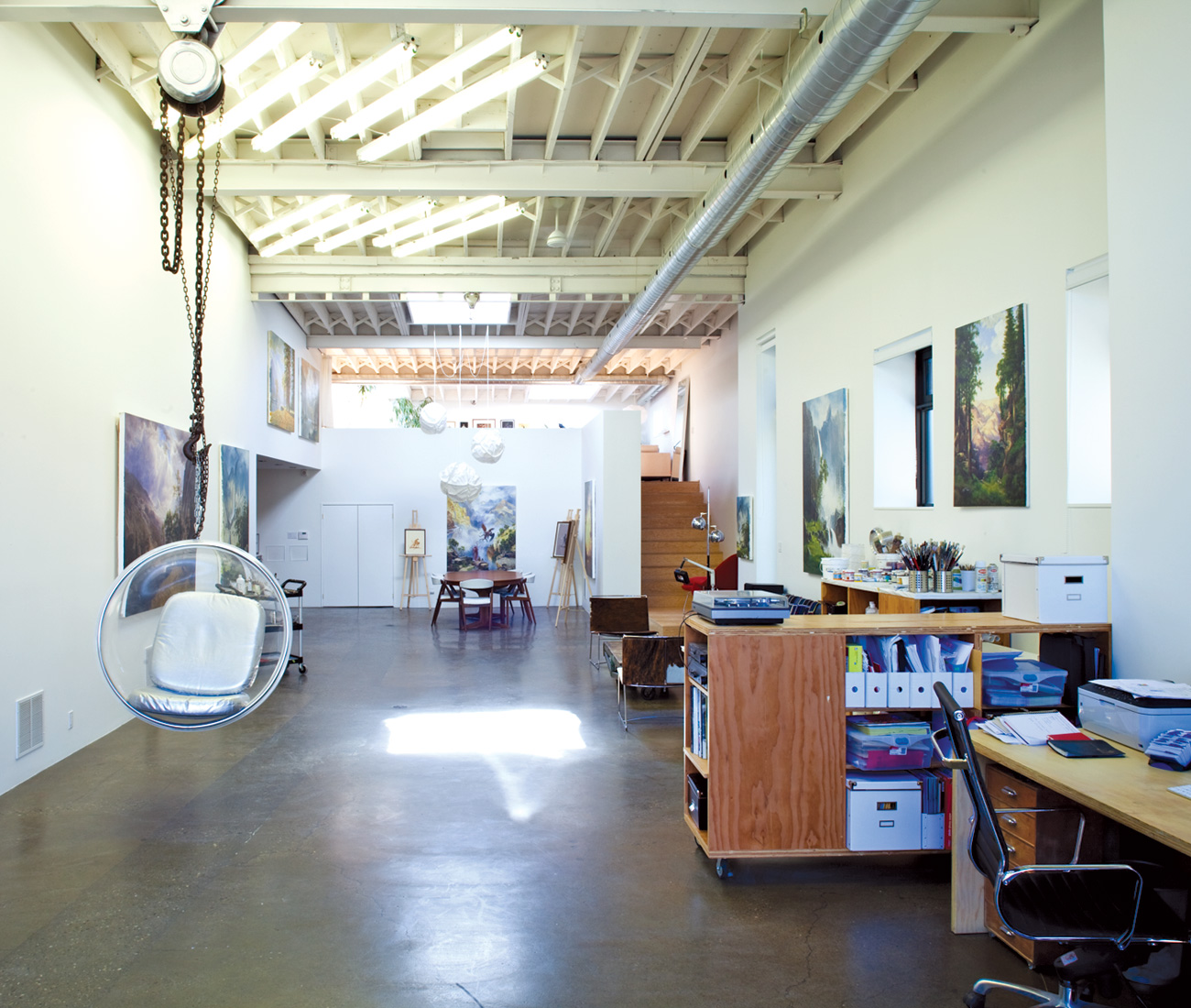 A 1960s-style bubble chair is suspended from an industrial winch, and Monkman’s painted landscapes hang throughout the studio.