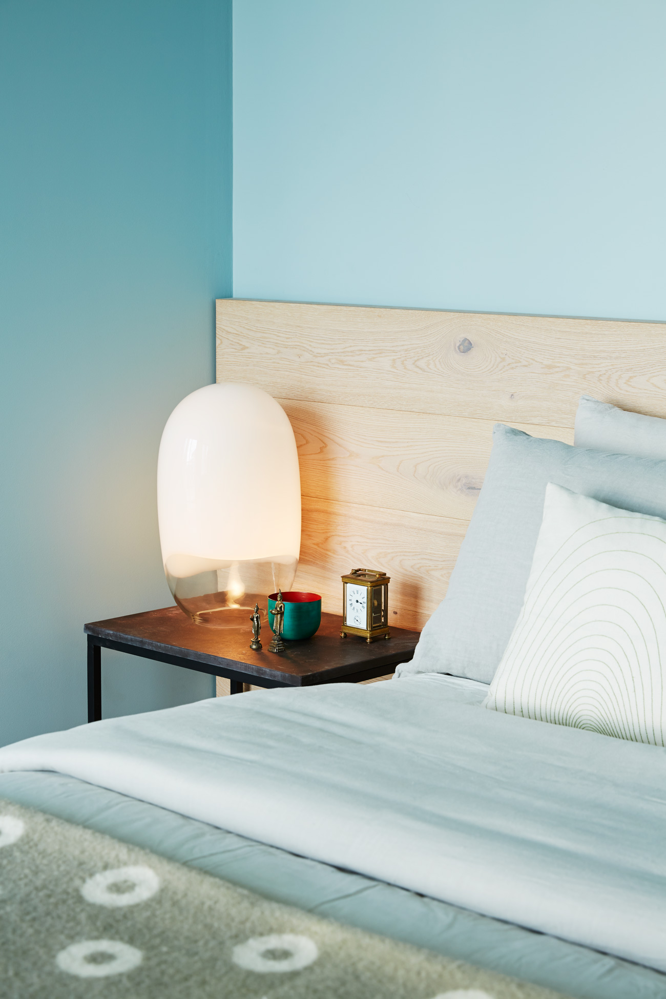 Surplus oak flooring was used to build a wall-to-wall headboard. The grey-blue picks up the wood’s muted veining. Vintage Ghost lamp from Zig Zag; blanket by Pia Wallen.