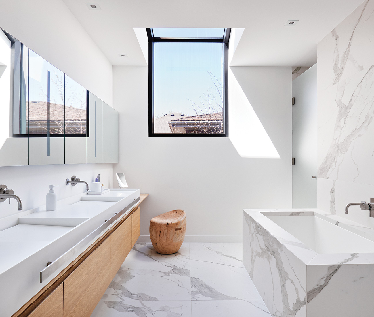Another roof window bathes the master bath in sunlight. Porcelain slabs from Stone Tile; soaker tub from Ginger’s; stool from Italinteriors.