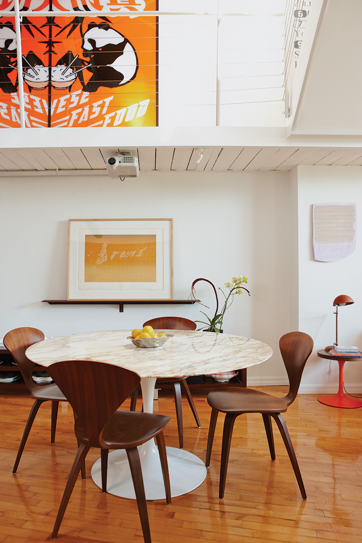 In the dining area is a marble-top Saarinen table with Cherner chairs, all from Quasi Modo. A screenprint by Ed Ruscha is propped on a picture ledge.