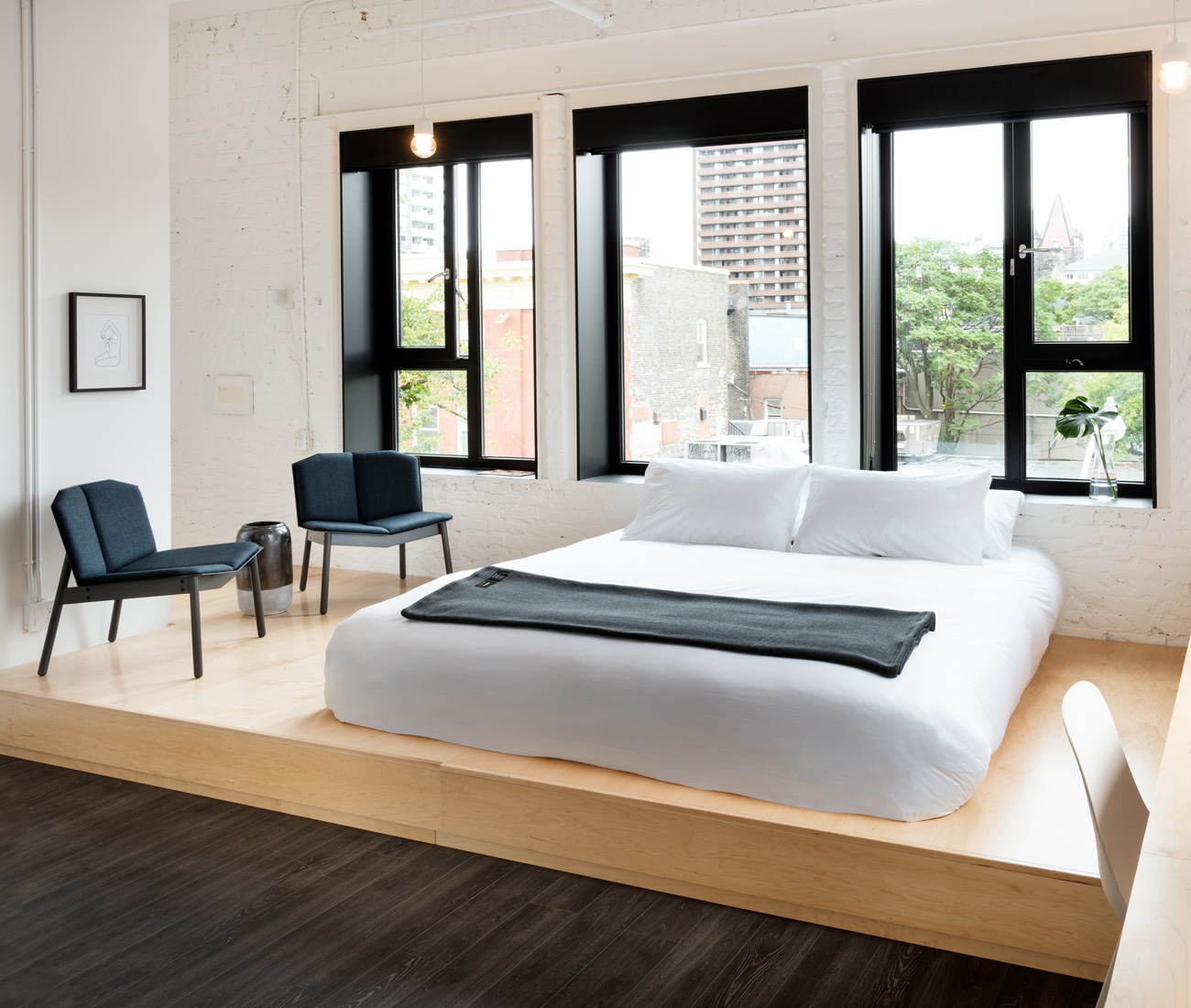 StudioAC’s custom-designed platform bed (made by RDG Millwork) has built-in cubbies. Cats Pajamas chair by Blu Dot, at Urban Mode; Ikea pendants.  