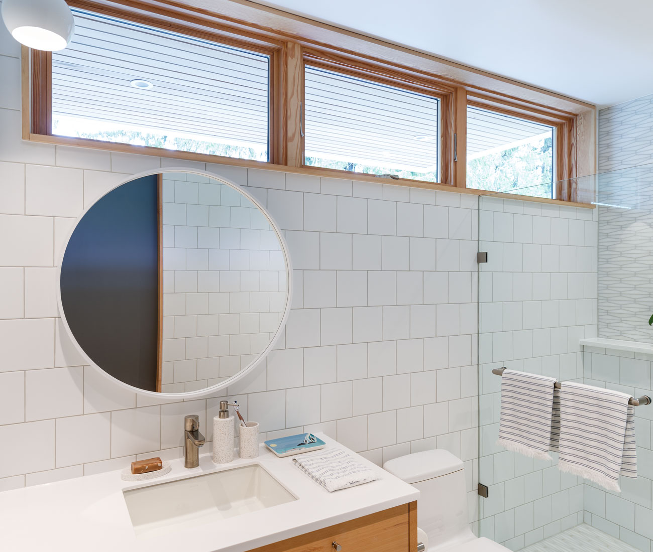 A round mirror contrasts with the linear details in the bathroom. 