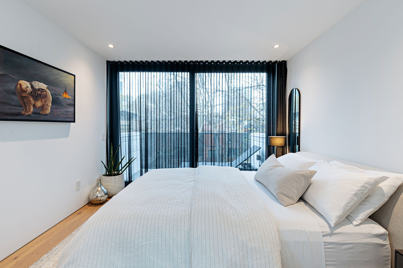 In the principal bedroom, a wall of sliding doors accesses a balcony that overlooks the backyard. Artwork, Richard Ahnert.