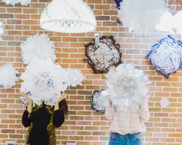 two people hiding behind pendant lights - Casa di Luce Showroom