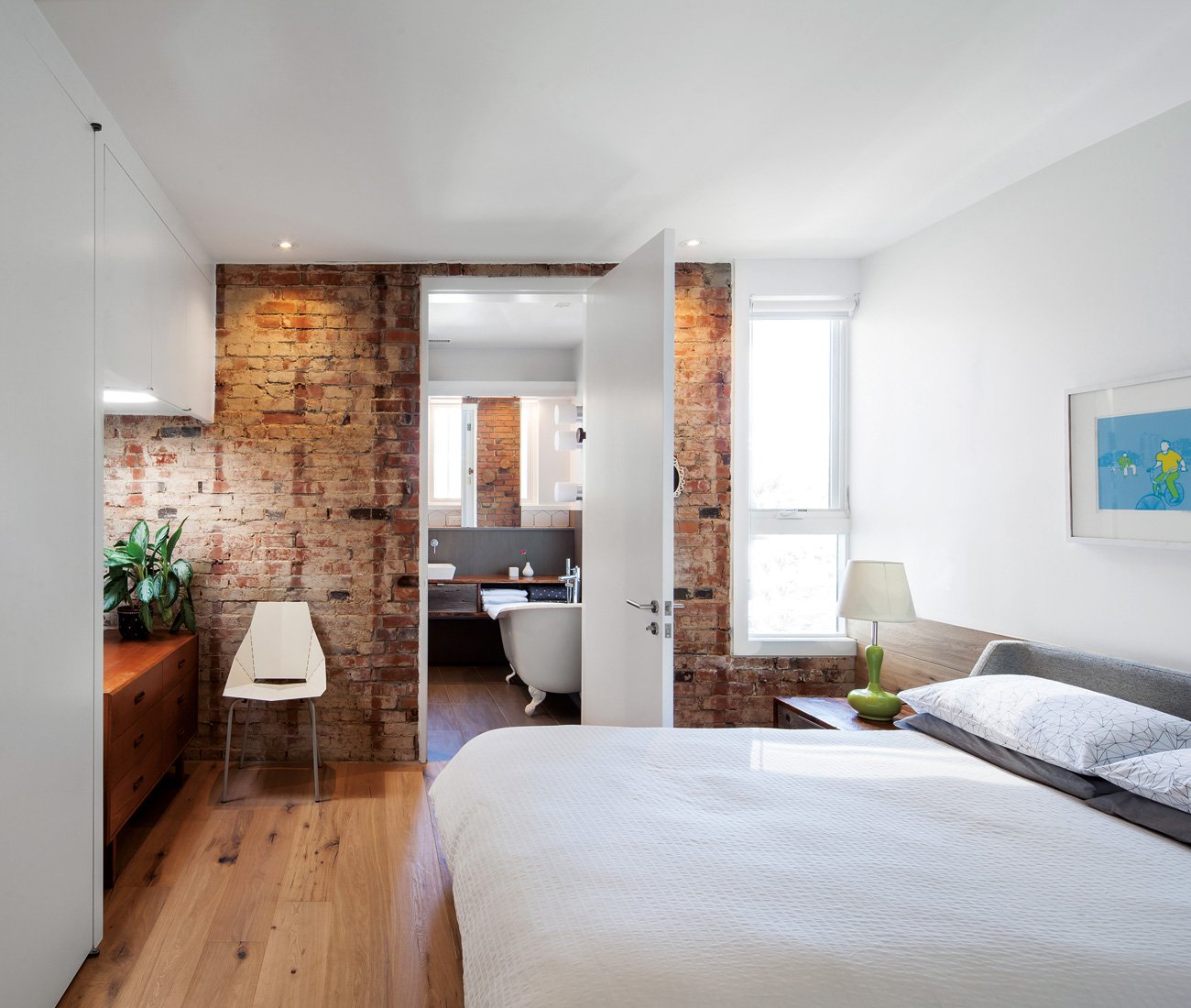 Master bedroom featuring an eastern brick wall, marking the transition between the original footprint and the new addition