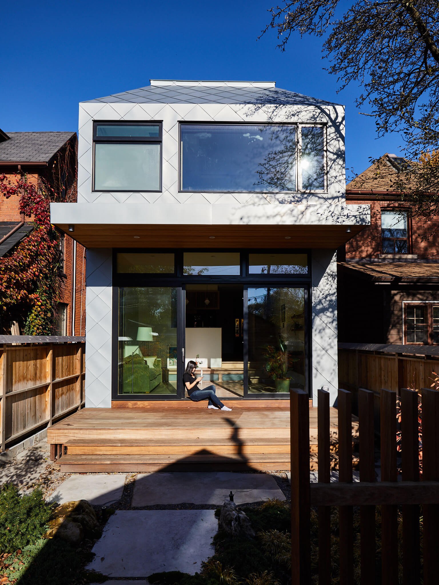 Exterior view of a modern back addition with a prismatic design clad in woven zinc, enhancing the original house's charm. Studio Junction