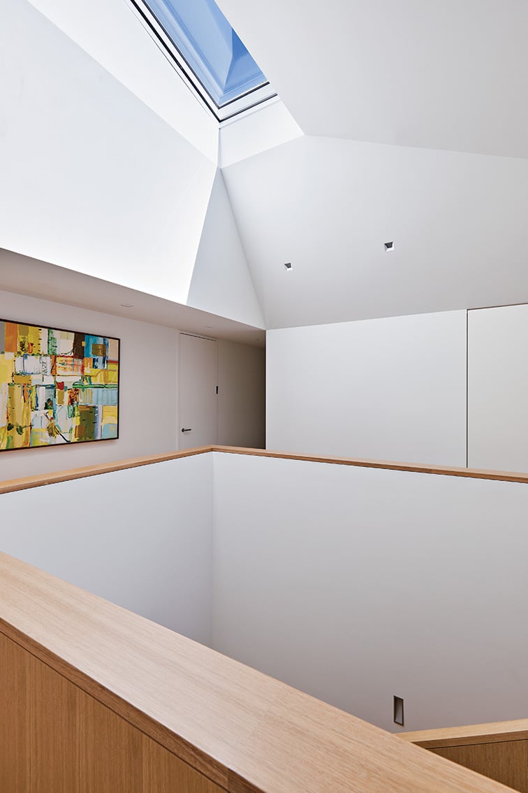 The second-storey landing opens up to a skylight that reaches nearly six metres above the main floor, design by AKB Architects