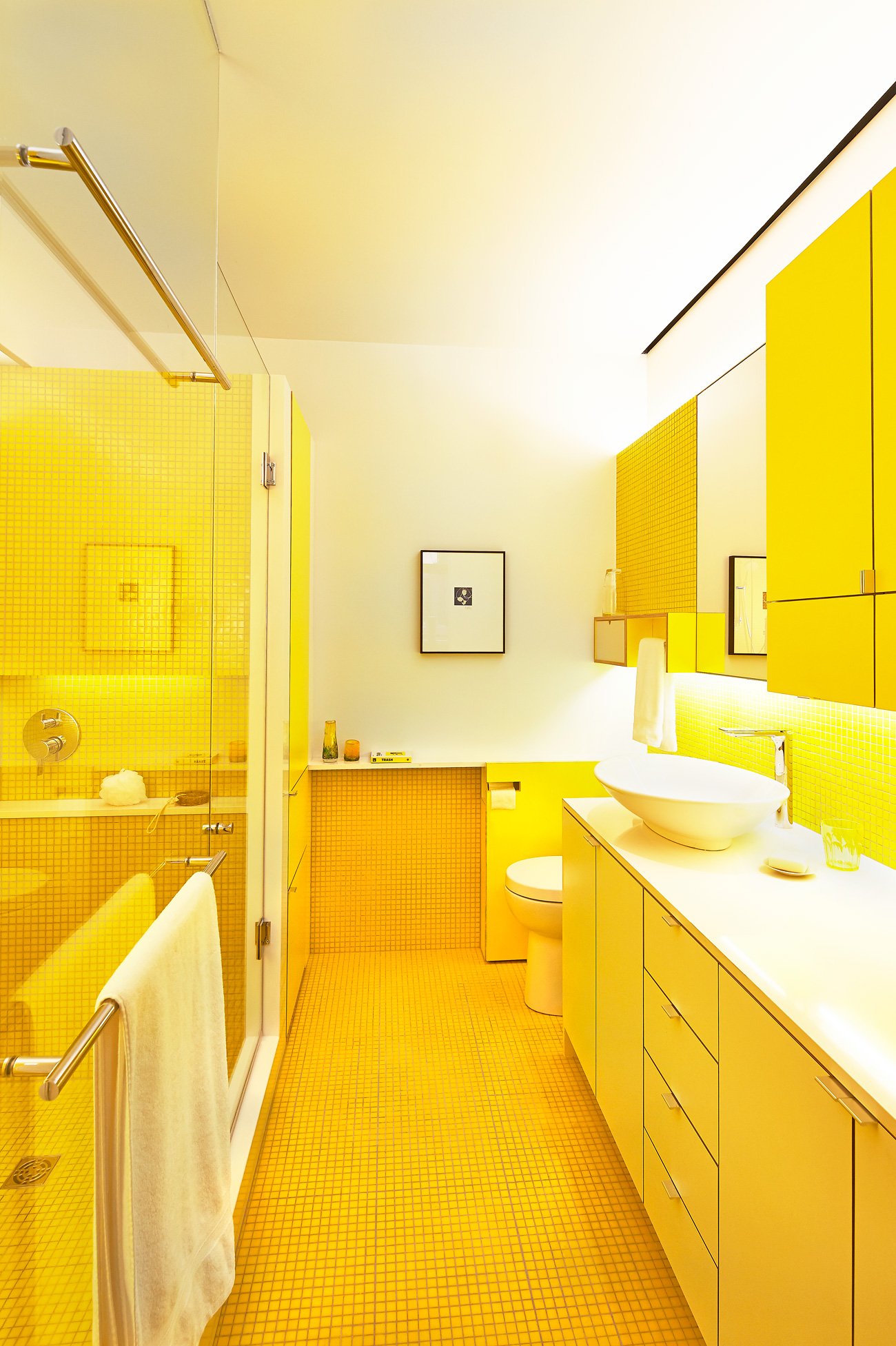 Yellow interiors with color-blocked bathroom and molten mosaic tiles.