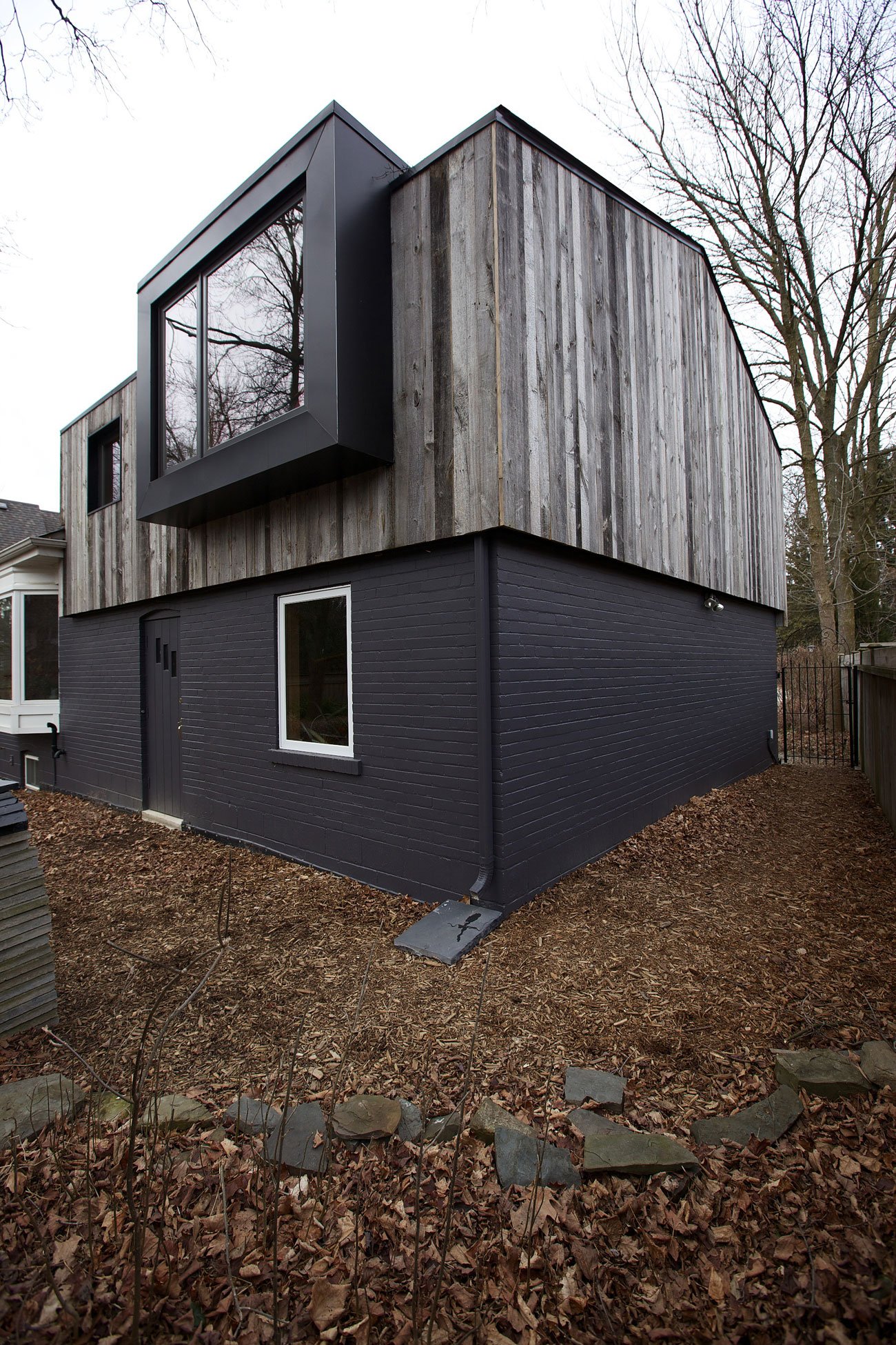 Exterior view of a cabin-inspired bungalow addition in Mississauga with a pitched roof and reclaimed barnboard siding by Design Architecture Everyday 