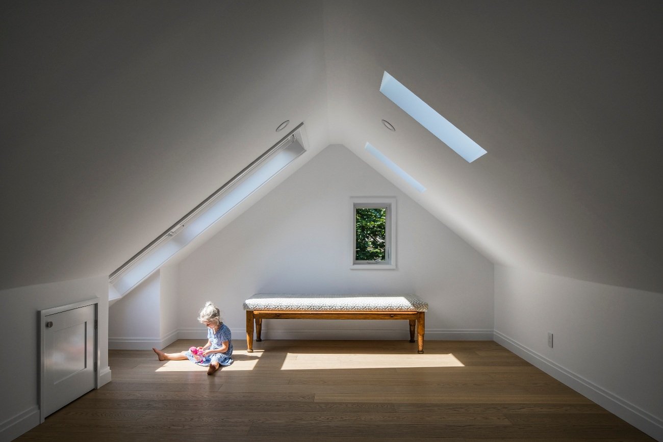 Light-filled attic space transformed into cozy bedrooms with integrated storage and stylish decor.
