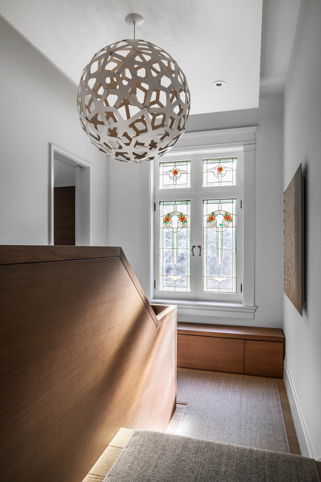 Sculptural dark oak central staircase connecting the main floor to the upper levels in a renovated Georgian home.