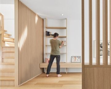 Minimalist renovation features a slatted wood screen that divides the layout, along with seamless storage and a vanishing vestibule bench