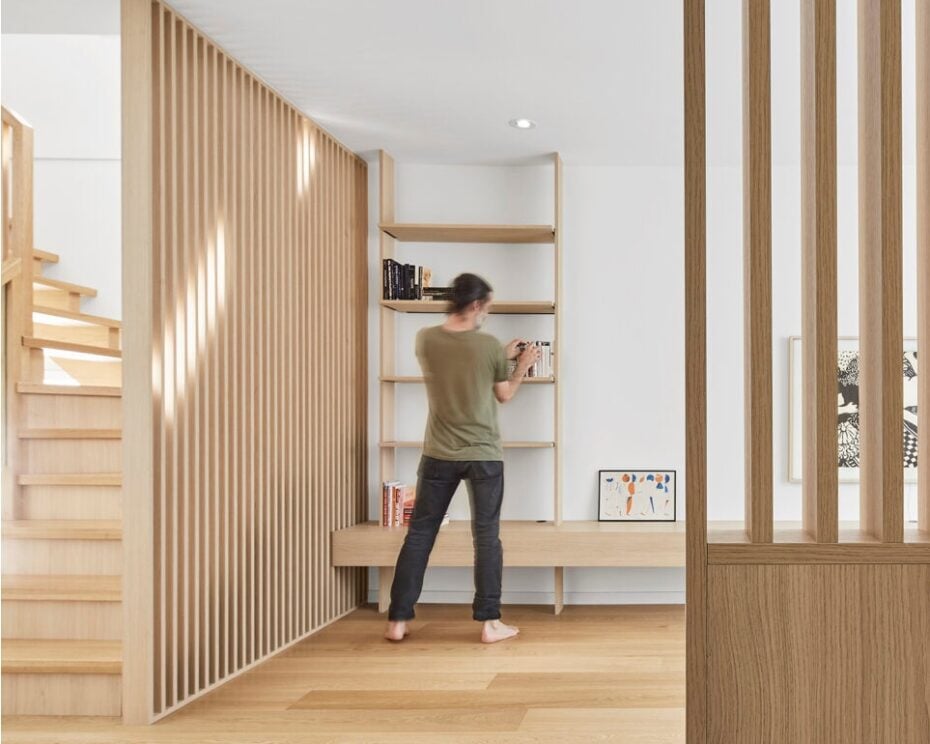 Minimalist renovation features a slatted wood screen that divides the layout, along with seamless storage and a vanishing vestibule bench